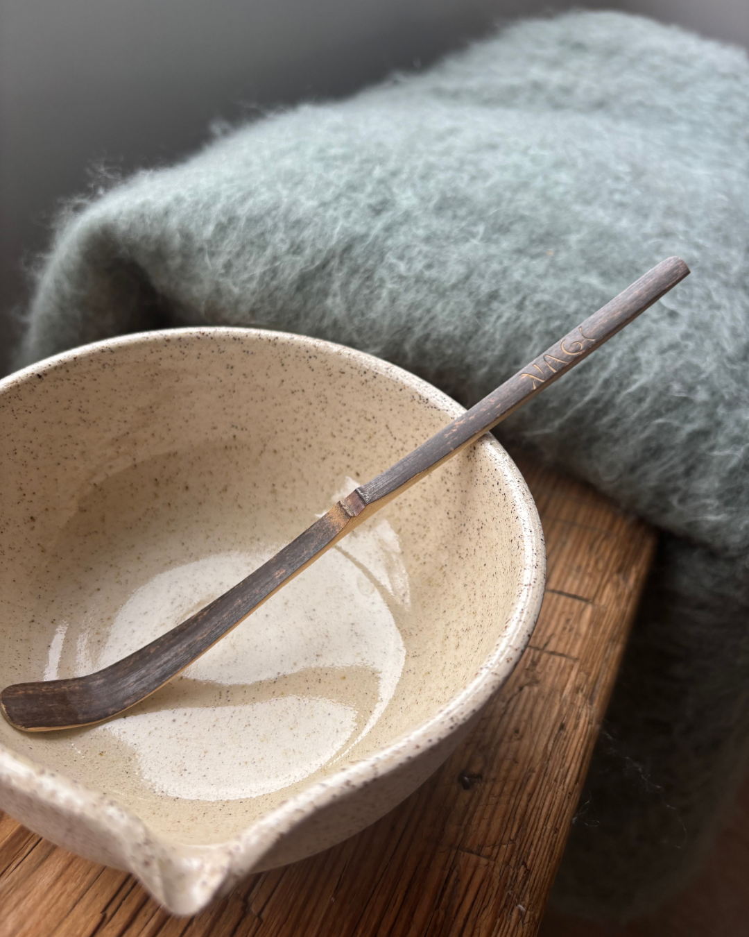 Nagi Matcha Bambo Spoon in a ceramic handmade bowl. The Nagi Matcha spoon  is handmade from sustainable dark bamboo